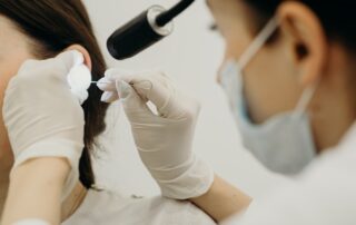 Arzt untersucht Ohr einer Patientin